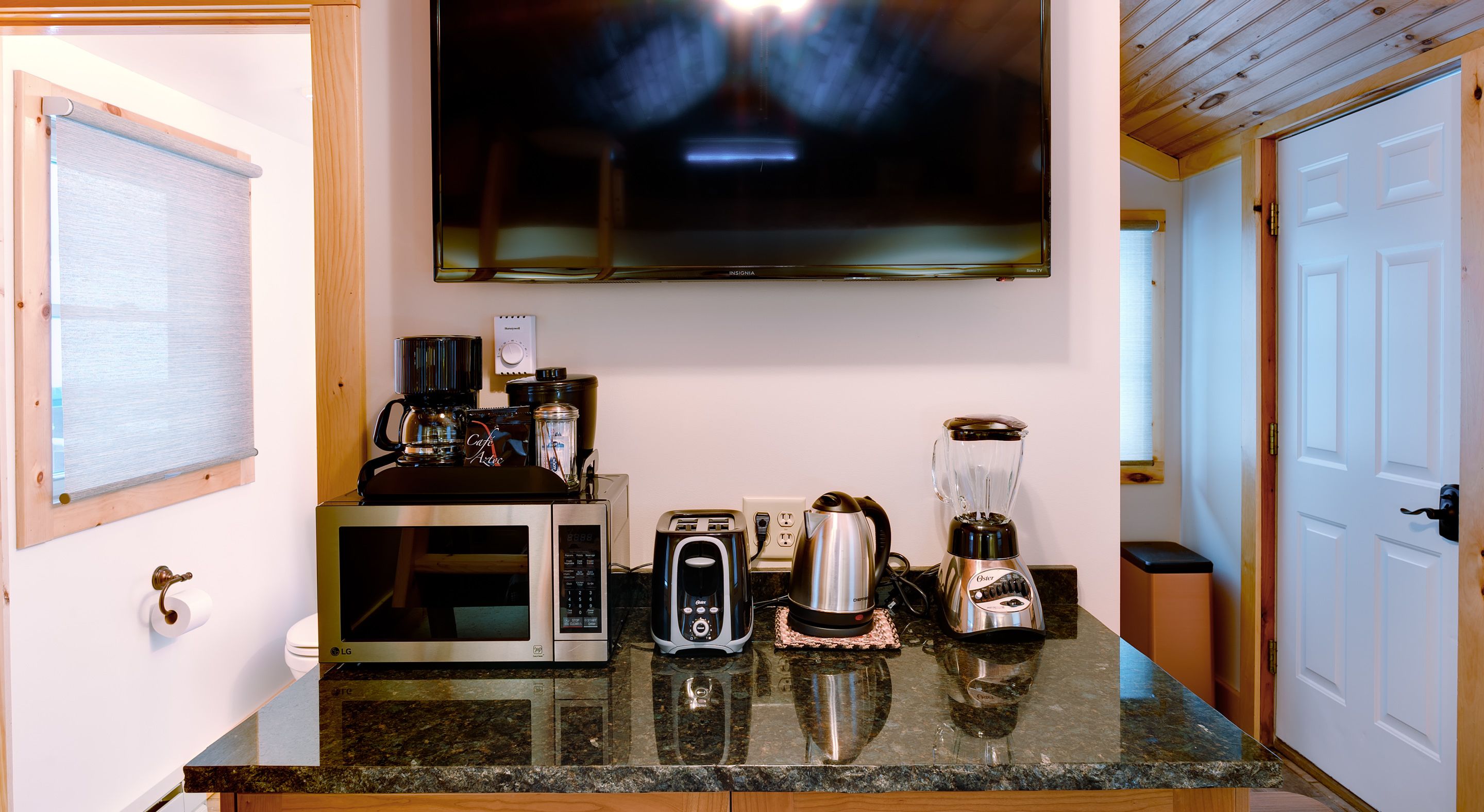 Una cocina con microondas, tostadora, cafetera y licuadora sobre la encimera.