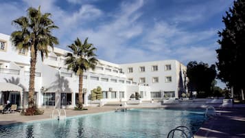 Una piscina al aire libre, sombrillas, sillones reclinables de piscina