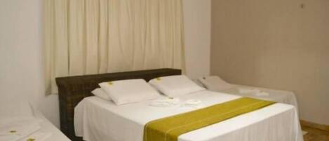Habitación de hotel con dos camas individuales, una cama grande y una cama separada a la izquierda.