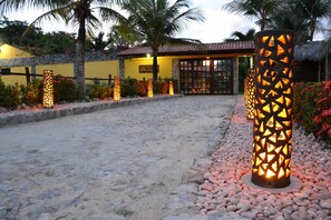 A pathway leading to a building with a stone wall and a thatched roof. - Pousada Maresias do Cumbuco (Caucaia)