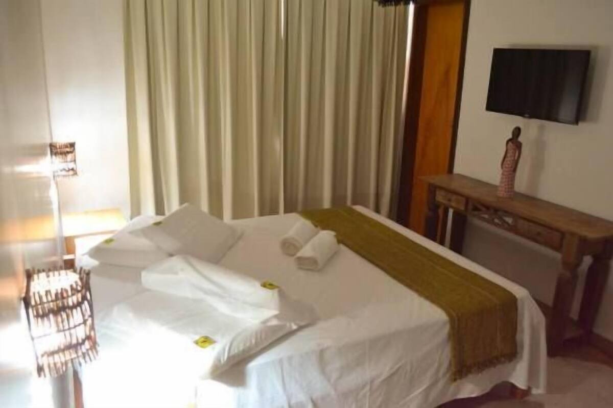 A hotel room with a bed, a desk, a television, and a curtain.