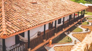 A traditional building with a tiled roof, a covered walkway, and a landscaped garden with gravel paths and plants. - Hotel Boutique Venturi (Barichara)