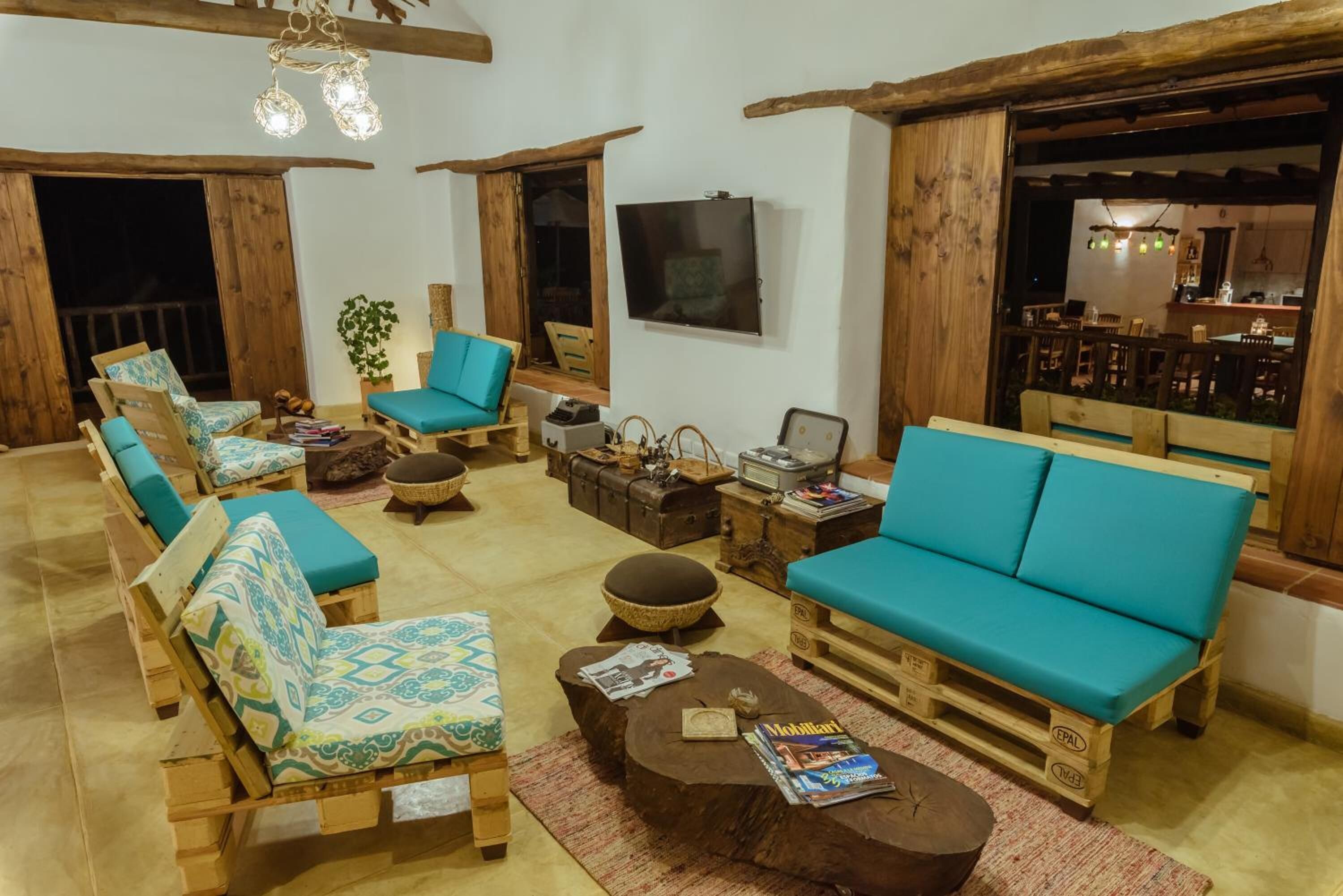 A cozy living room with wooden furniture, a television, and a dining area visible through an open door.
