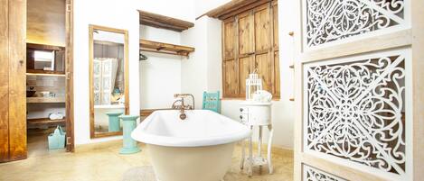Un baño con una bañera independiente, armarios de madera y paneles decorativos.
