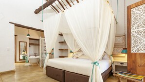 A bedroom with a bed under a canopy, a wooden bench, a nightstand, and a bathroom with a bathtub and sink. - Hotel Boutique Venturi (Barichara)