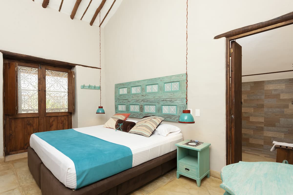 A bedroom with a bed, bedside table, and a headboard with decorative panels.