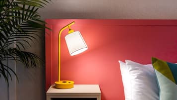 A neatly made bed with white linens, a red headboard, and a bedside table with a yellow lamp.