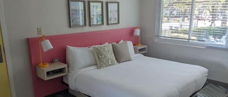 A neatly arranged bedroom with a bed, bedside lamps, a nightstand, and a window with blinds.