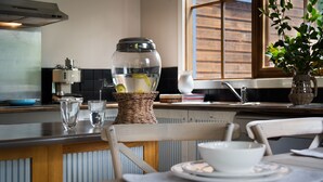 A kitchen with a dining table, chairs, a basket with lemons, a glass jar, and a potted plant. - French Cottage (Hepburn Springs)