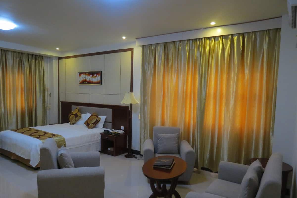 A hotel room with two beds, a sofa, a coffee table, and curtains.
