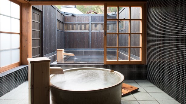 A traditional Japanese-style room with a wooden bathtub, a wooden cabinet, and a large window offering a view of the outside. - Miyama Sanso (Minamioguni)