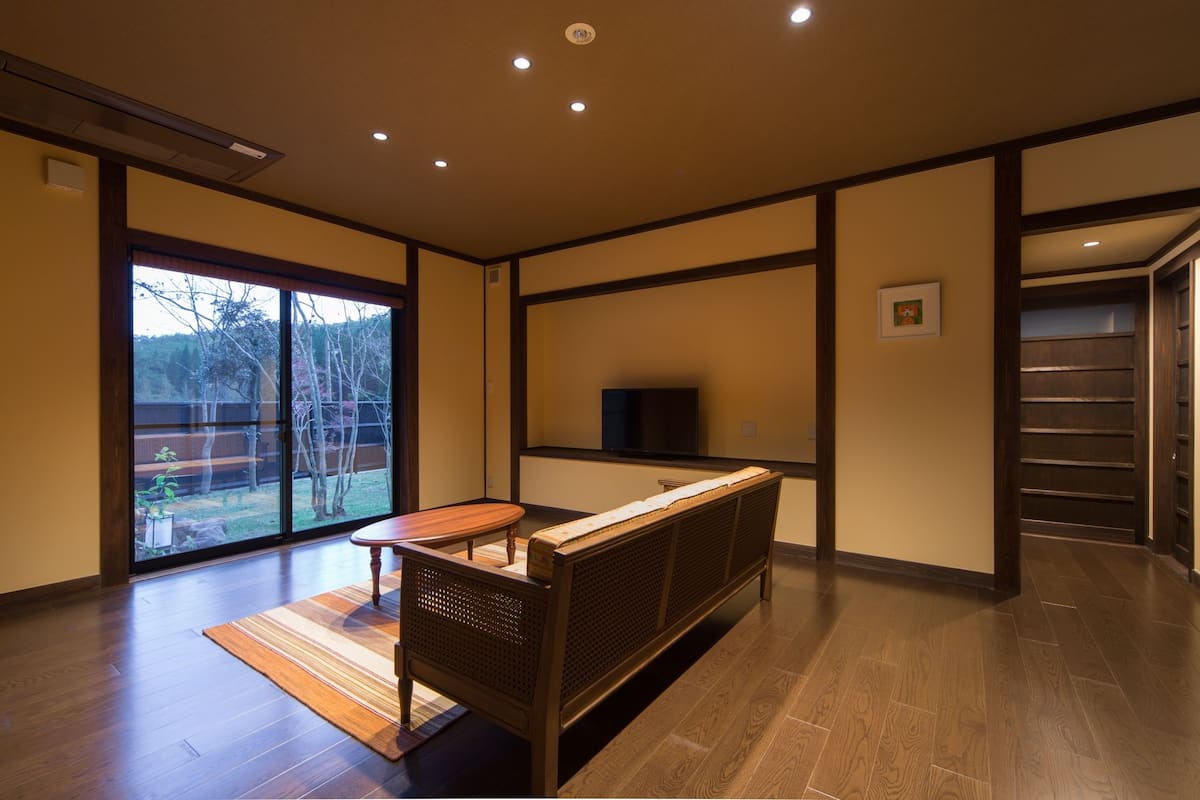 A modern interior with a wooden bench, a small table, and a TV on a stand.