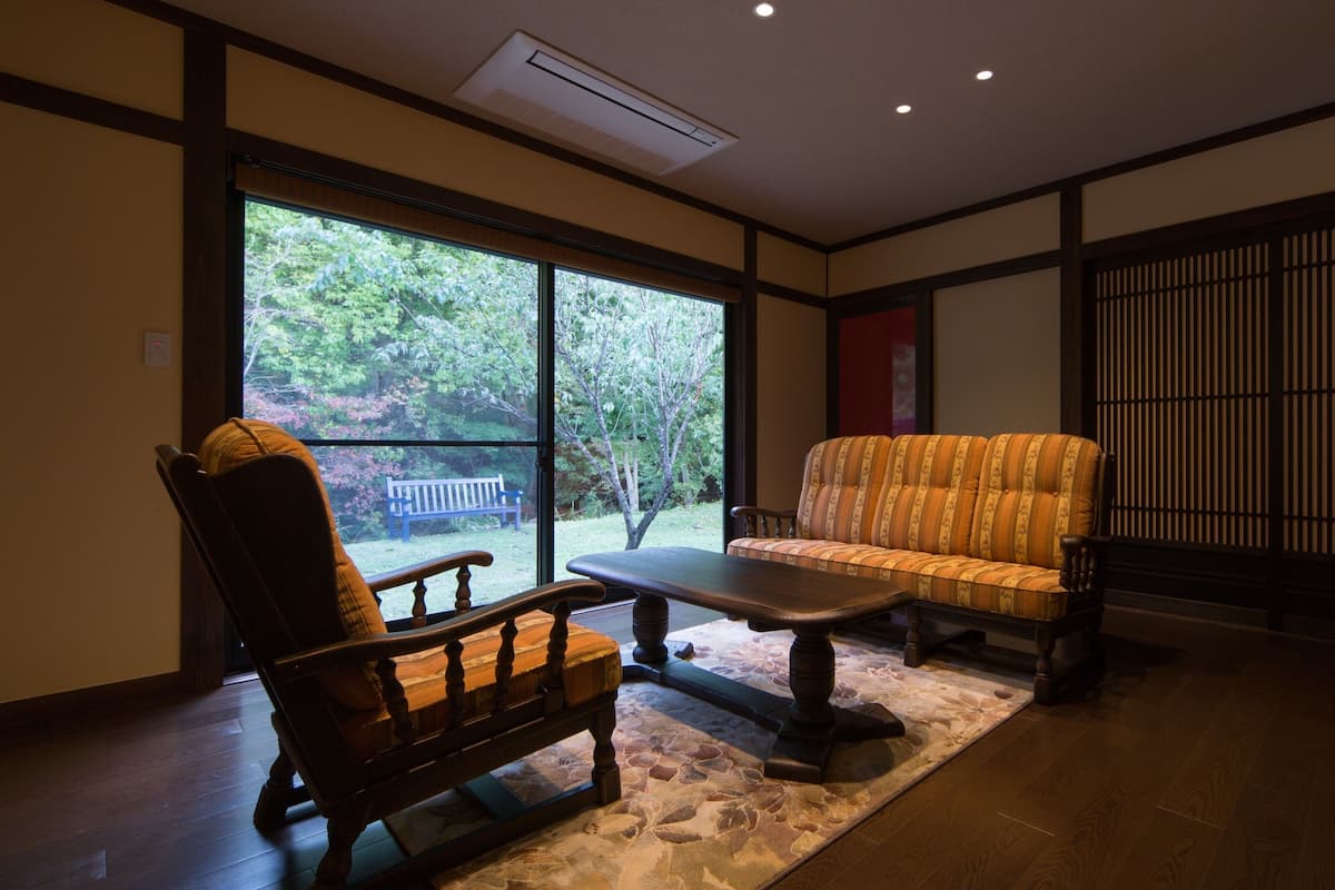 A room with a large window, a wooden bench, a sofa, and a small table.