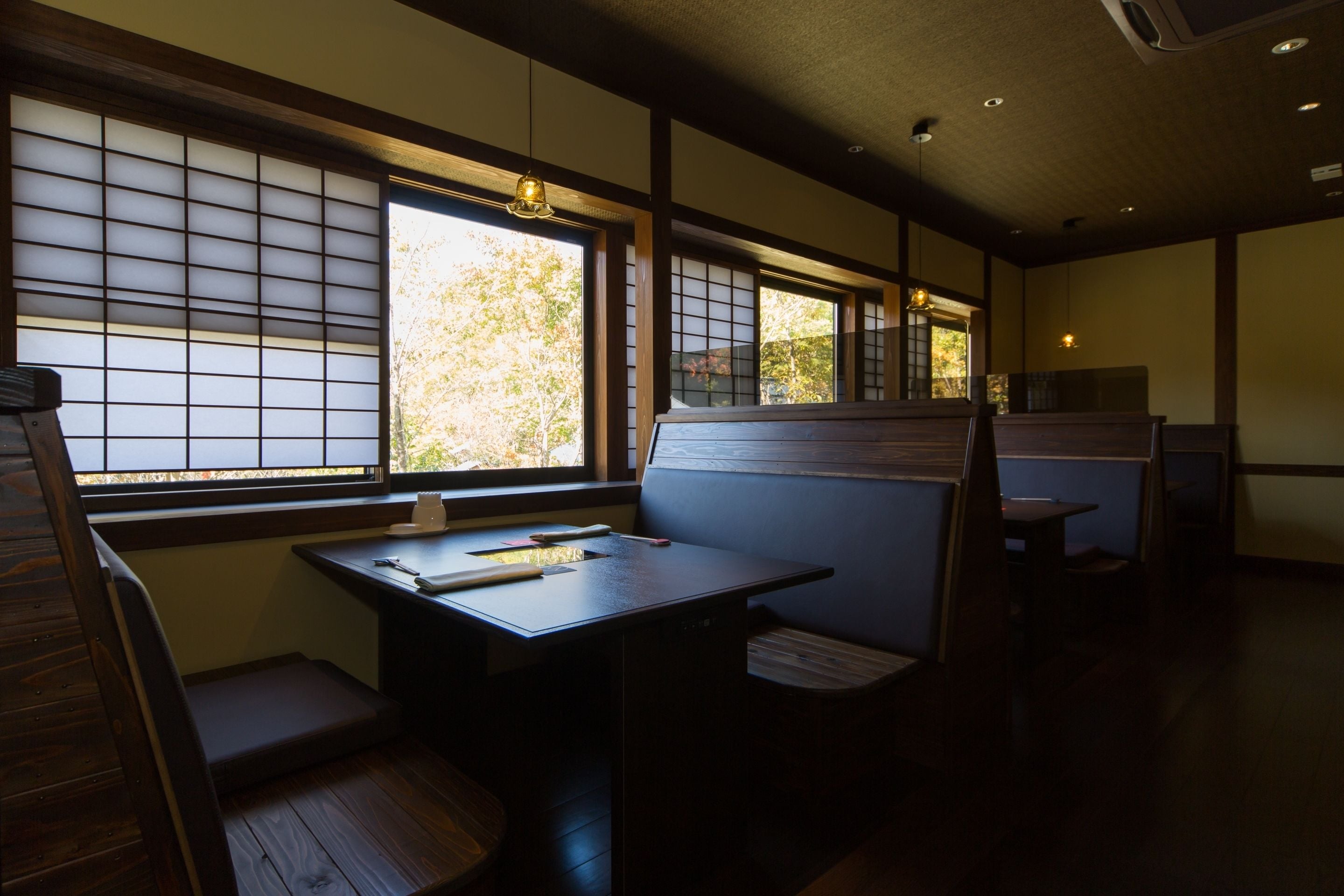 Um quarto em estilo japonês tradicional, com piso de tatame, portas deslizantes shoji e uma mesa baixa com um banco.