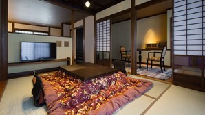 A traditional Japanese-style room with tatami flooring, a low platform bed, a television, and sliding doors. - Miyama Sanso (Minamioguni)