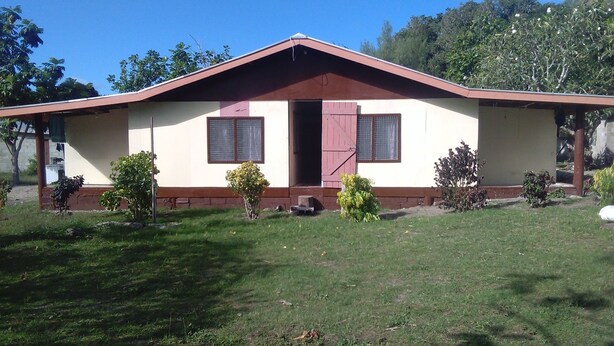 Une maison de plain-pied avec un toit à deux versants, une porte d’entrée et deux fenêtres dotées de volets.
