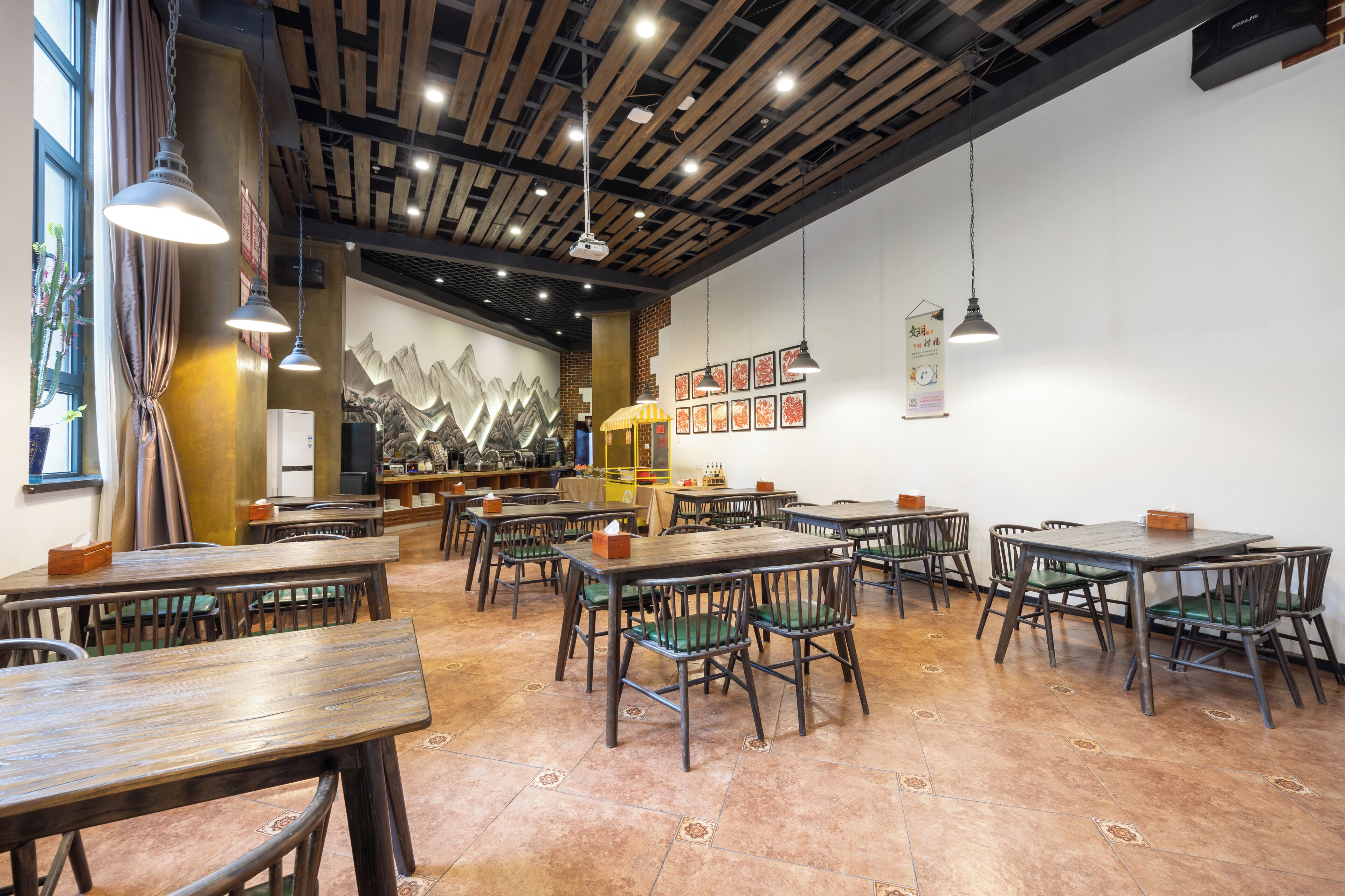 A restaurant with wooden tables and chairs, hanging lights, and a mural on the wall.