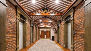 A hallway with brick walls, wooden beams, and patterned carpet.