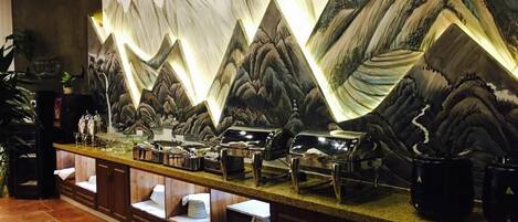 A bar area with a wall mural of mountains, a counter with various items, and a tiled floor.