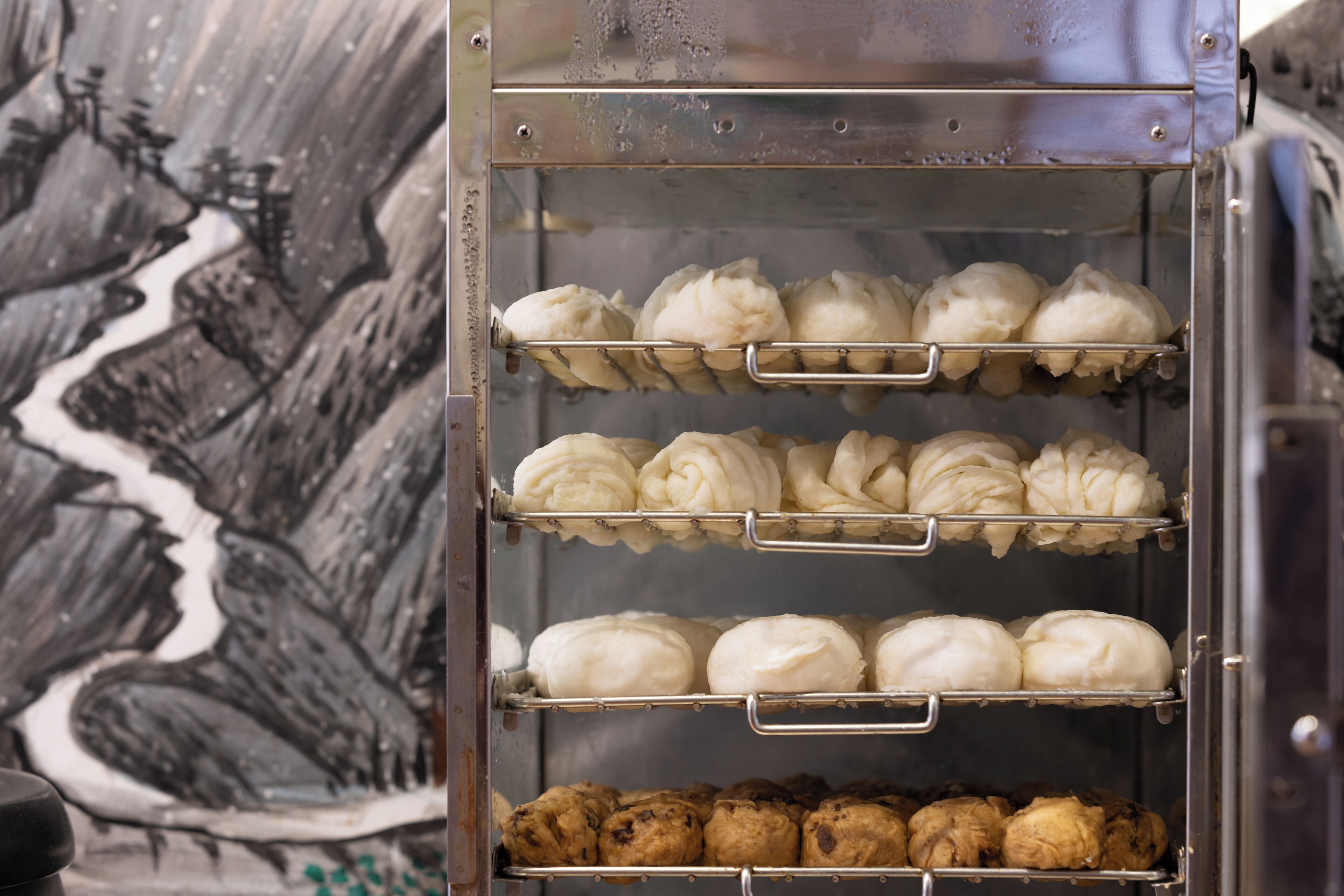 A bakery display case with three shelves of baked goods.