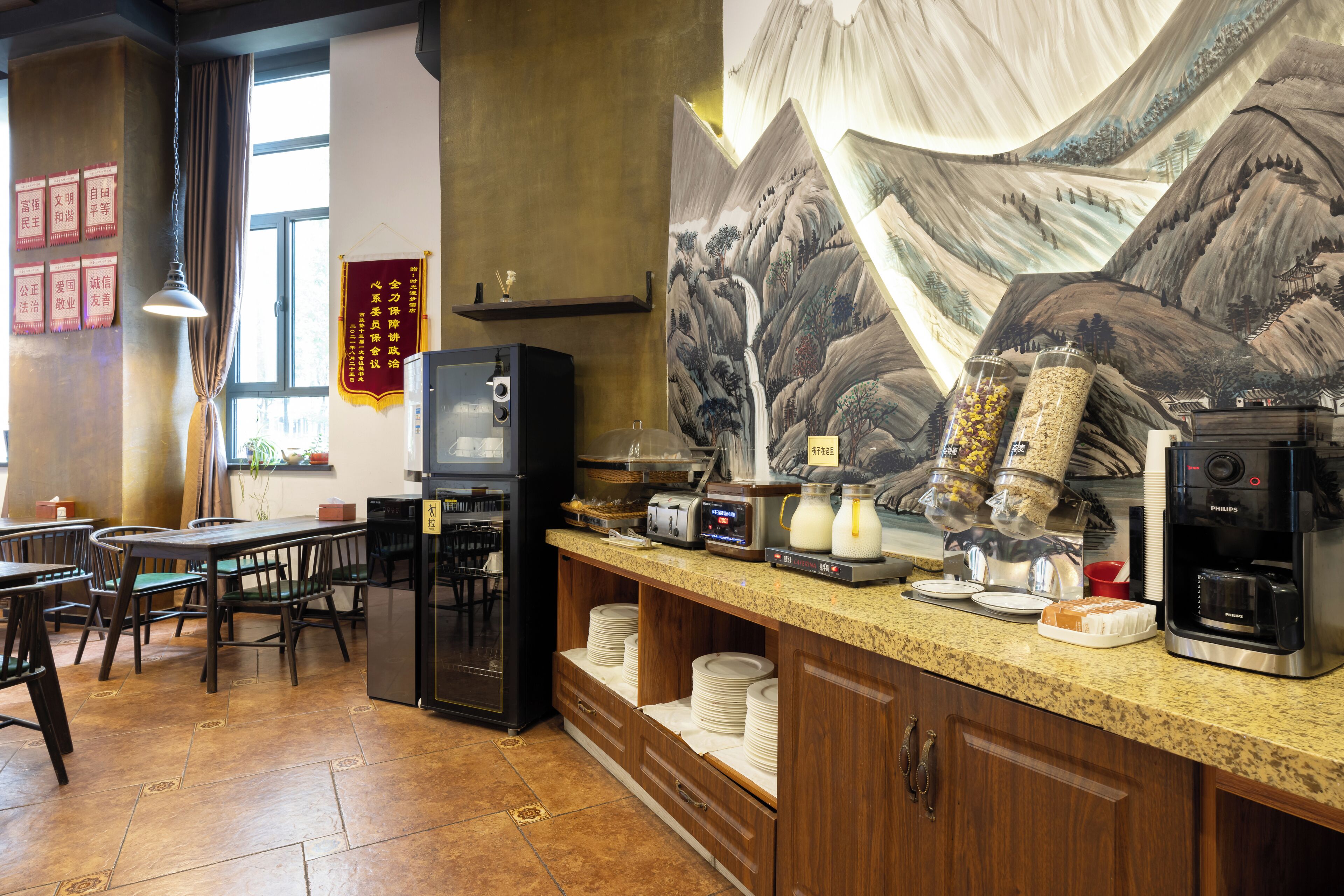 A restaurant with a counter, chairs, a refrigerator, and a coffee machine.