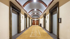 A hotel hallway with a carpeted floor, wooden doors, and a ceiling with recessed lighting.