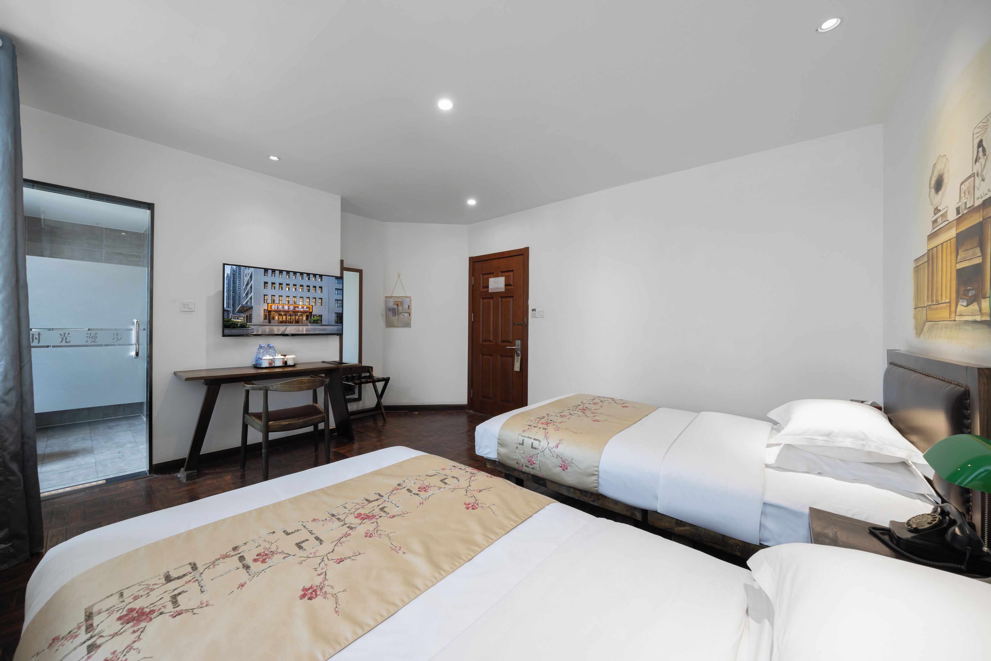 Une chambre d’hôtel avec deux lits, un bureau, une chaise et un téléviseur.