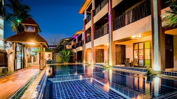 A hotel pool area with a tiled floor, a covered seating area, and a building with multiple balconies. - The LD Pattaya (Pattaya)