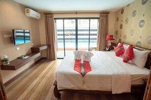 Ett hotellrum med en säng, en tv, ett skrivbord och utsikt över stranden genom de skjutbara dörrarna.