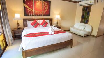 A hotel room with a large bed, two bedside lamps, a white sofa, and a decorative wall piece.
