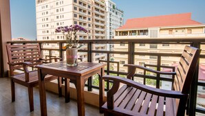Ein Balkon mit Holzmöbeln, einer Topfpflanze und Blick auf die umliegenden Gebäude.