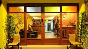 A hostel entrance with a 'Welcome' mat, two wicker chairs, and a 'Fellow Hostel' sign. - Fellow Hostel (Chiang Mai)