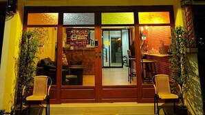 A two-story building with a ground-level entrance, a visible interior with a counter and seating, and air conditioning units on the exterior. - Fellow Hostel (Chiang Mai)