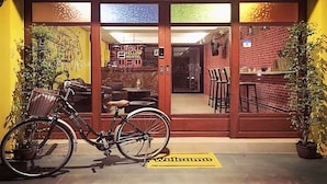 A bicycle parked outside a building with a 'Welcome' mat and a sign indicating a hostel. - Fellow Hostel (Chiang Mai)