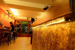 Een bar met een bakstenen muur, hangplanten en een kat zittend op de toonbank.