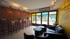 A modern bar area with brick walls, bar stools, and a black leather couch. - Fellow Hostel (Chiang Mai)