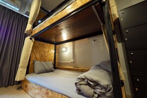 A bunk bed with a wooden headboard, a bedside table with a light, and a hanging coat rack. - Fellow Hostel (Chiang Mai)