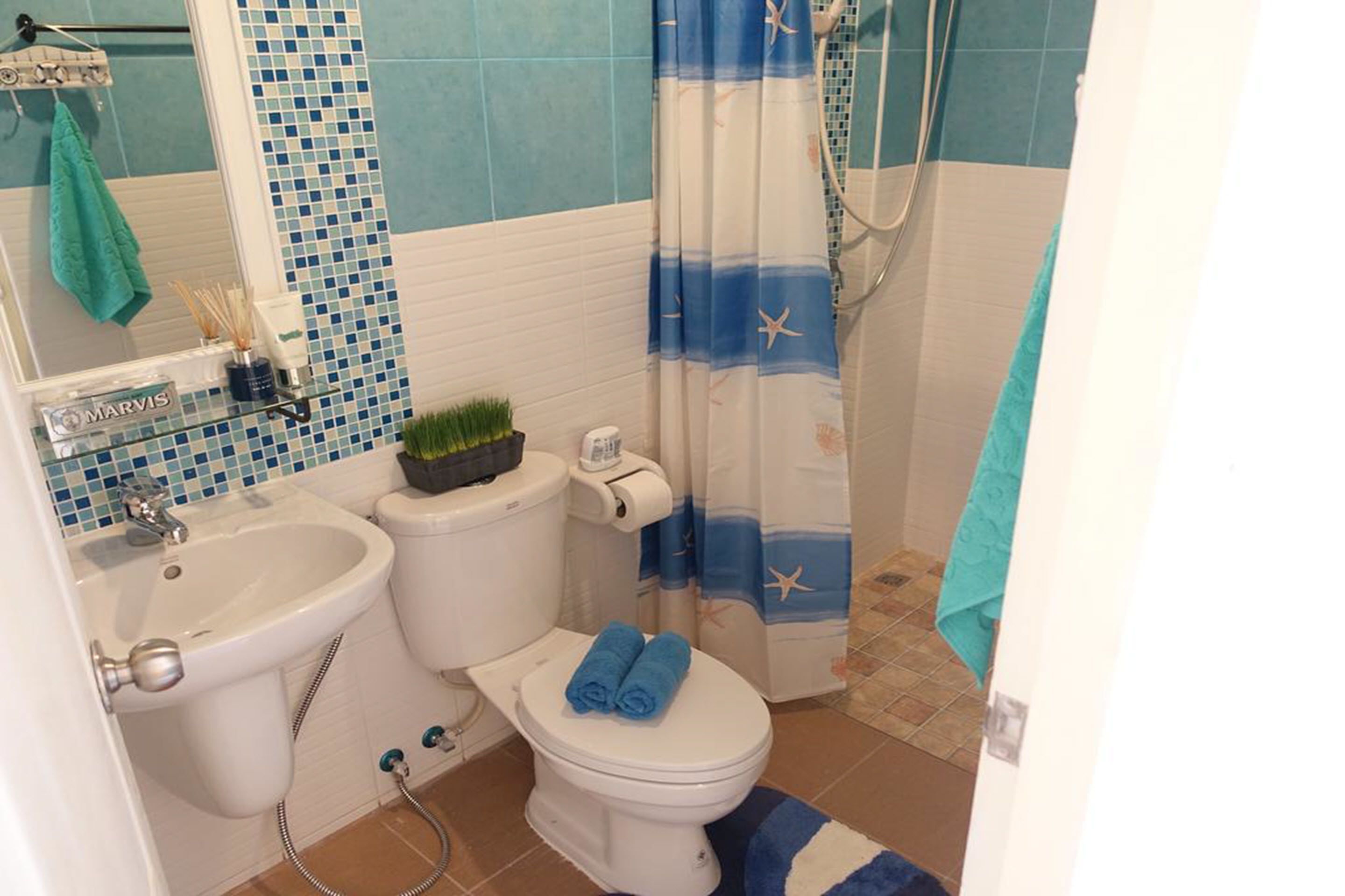 A bathroom with a toilet, bidet, and sink. There is a shower curtain with a starfish pattern.