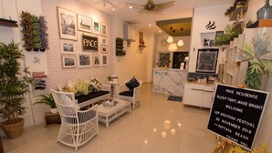 A modern hotel lobby with a white brick wall, framed pictures, and a reception desk. - Pace Residence Pattaya (Pattaya)