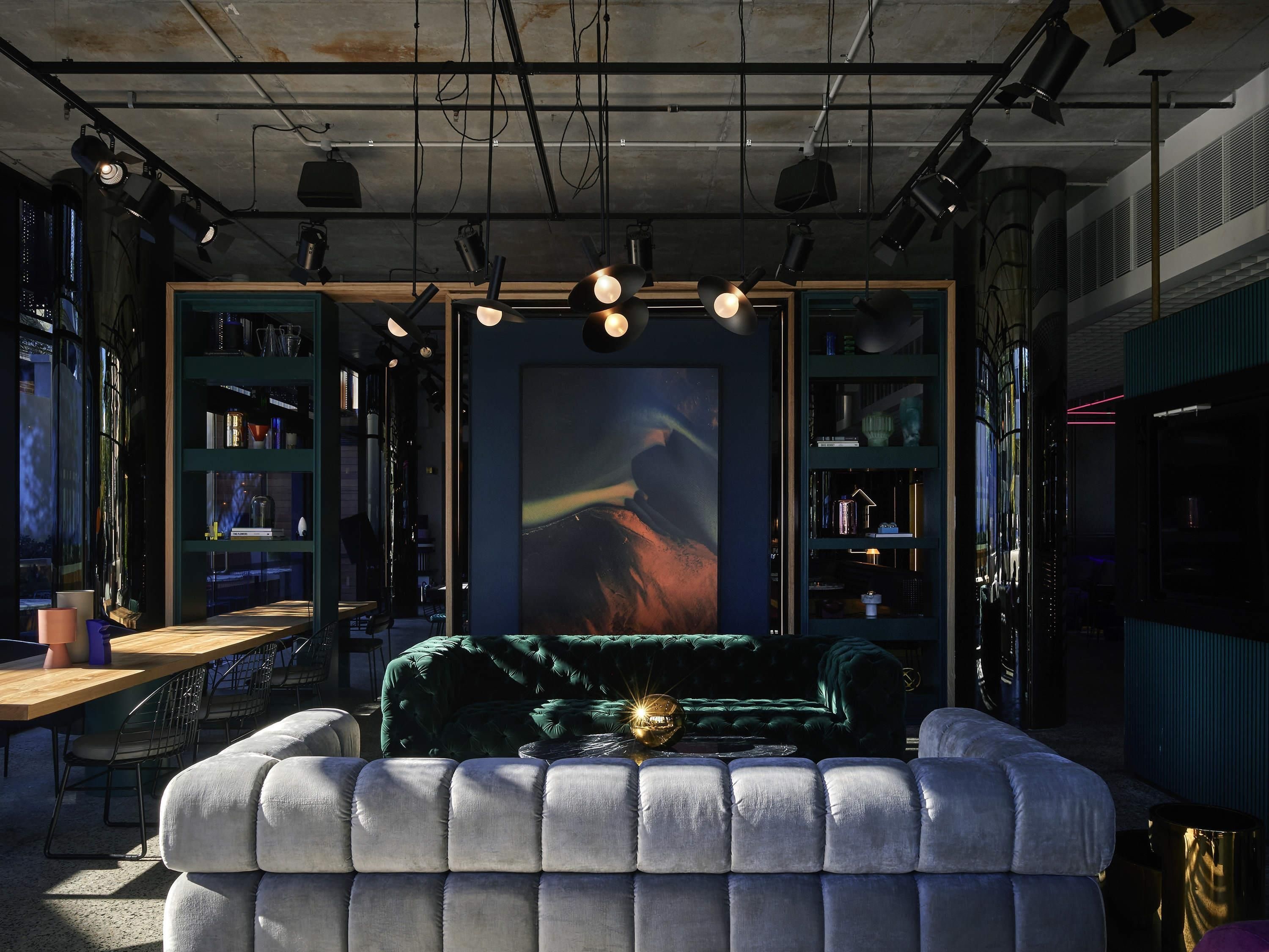 A modern living room with a plush sofa, a large abstract painting, and a bookshelf filled with books and decorative items.