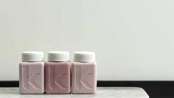Tres botellas iguales con tapas blancas y un logotipo sobre una superficie de mármol.