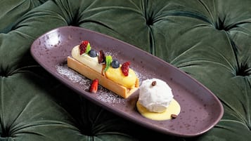A dessert on a plate on a tufted green sofa.