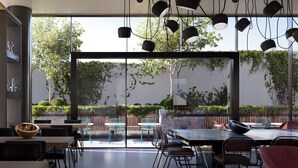 An indoor dining area with large windows, modern lighting, and outdoor seating. - Tribe Perth Kings Park (West Perth)