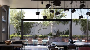 Un espace de restauration intérieur doté de grandes fenêtres, d’un éclairage moderne et d’une terrasse.