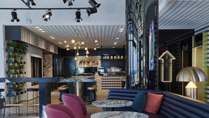 A modern bar area with marble-topped tables, plush seating, and a bar counter with a coffee machine.