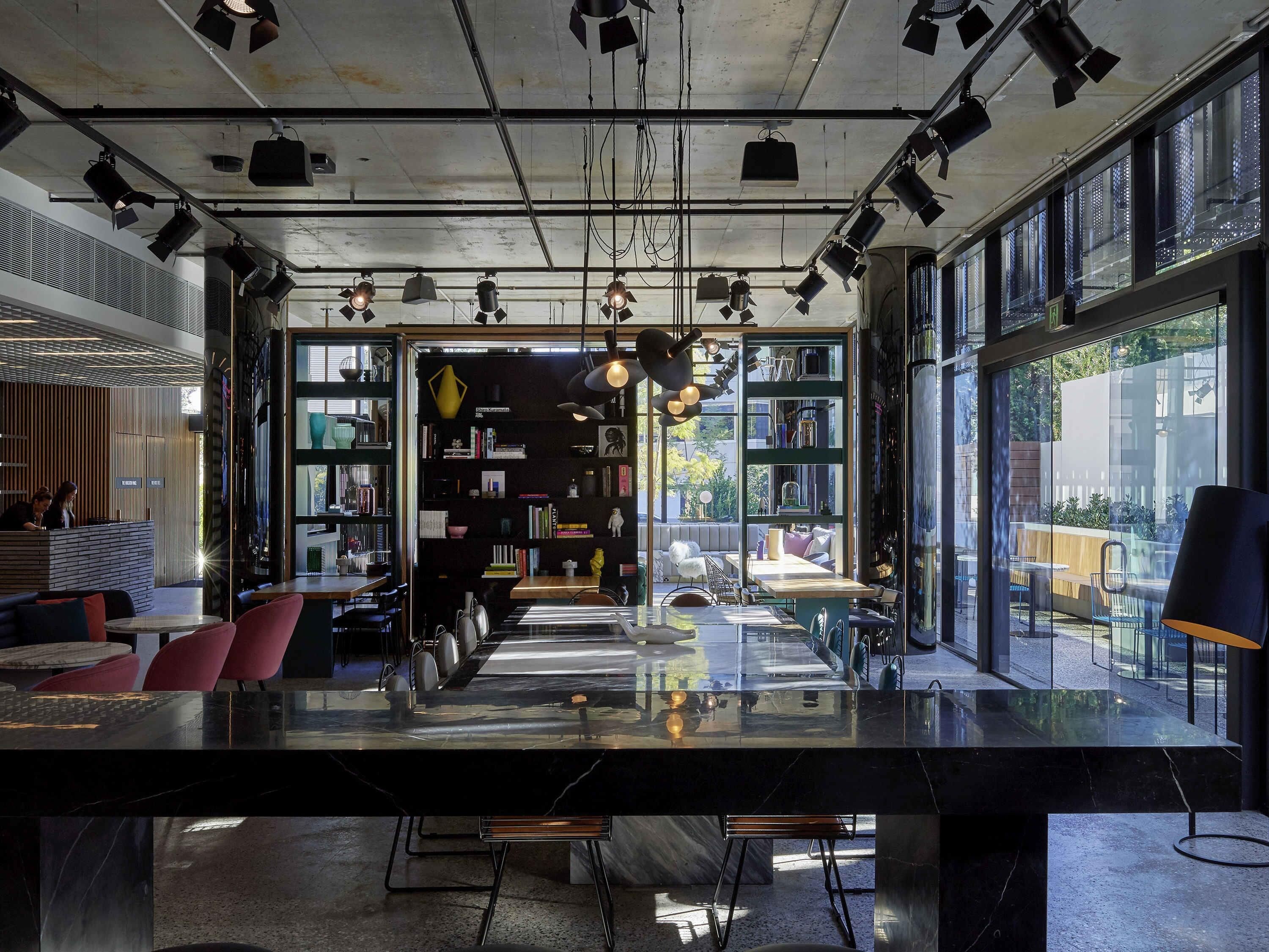 A modern interior with a long dining table, bookshelves, and a reception area.