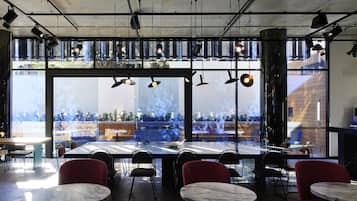 A modern dining area with large windows, multiple tables, and chairs.