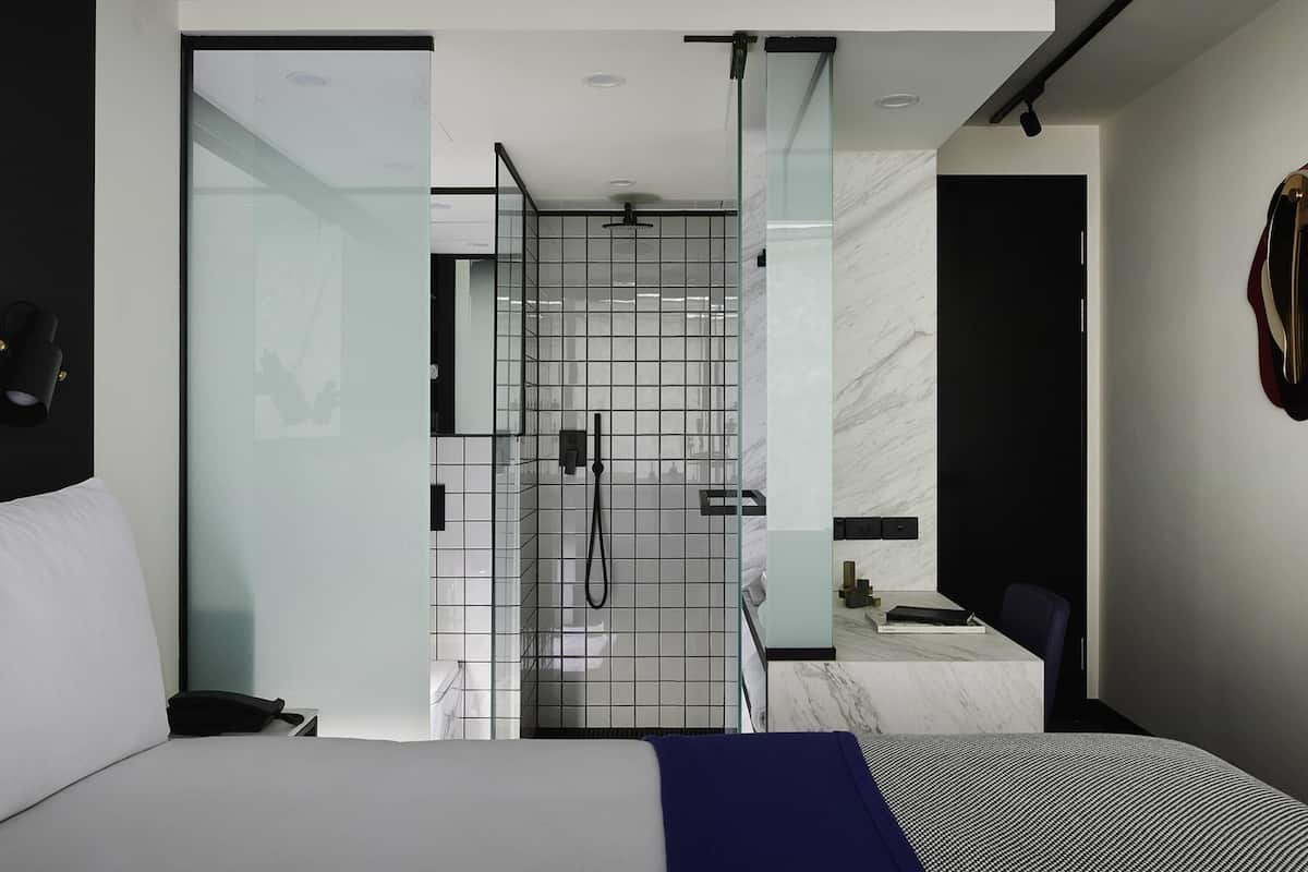 Une chambre d’hôtel moderne équipée d’un lit, d’une douche et d’un petit bureau.