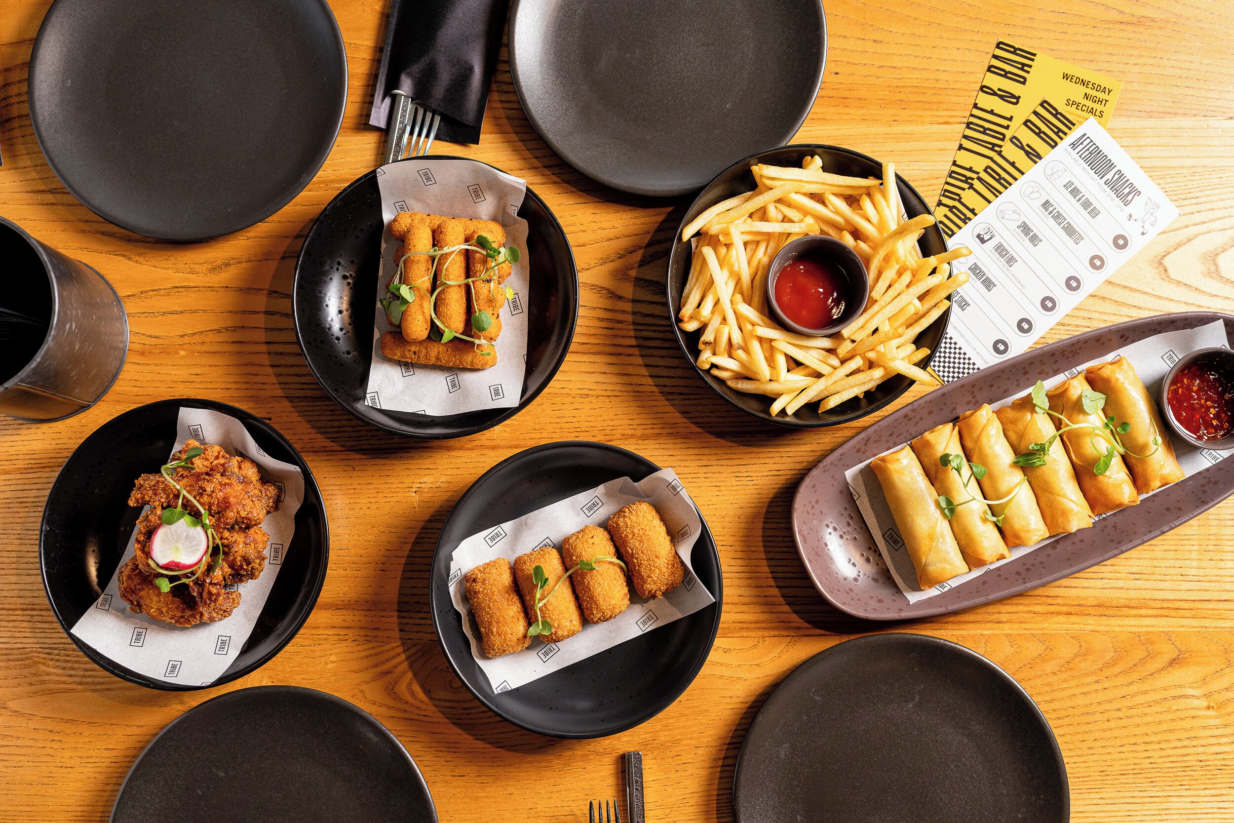 A table with various dishes, including fried items and fries, and a menu.