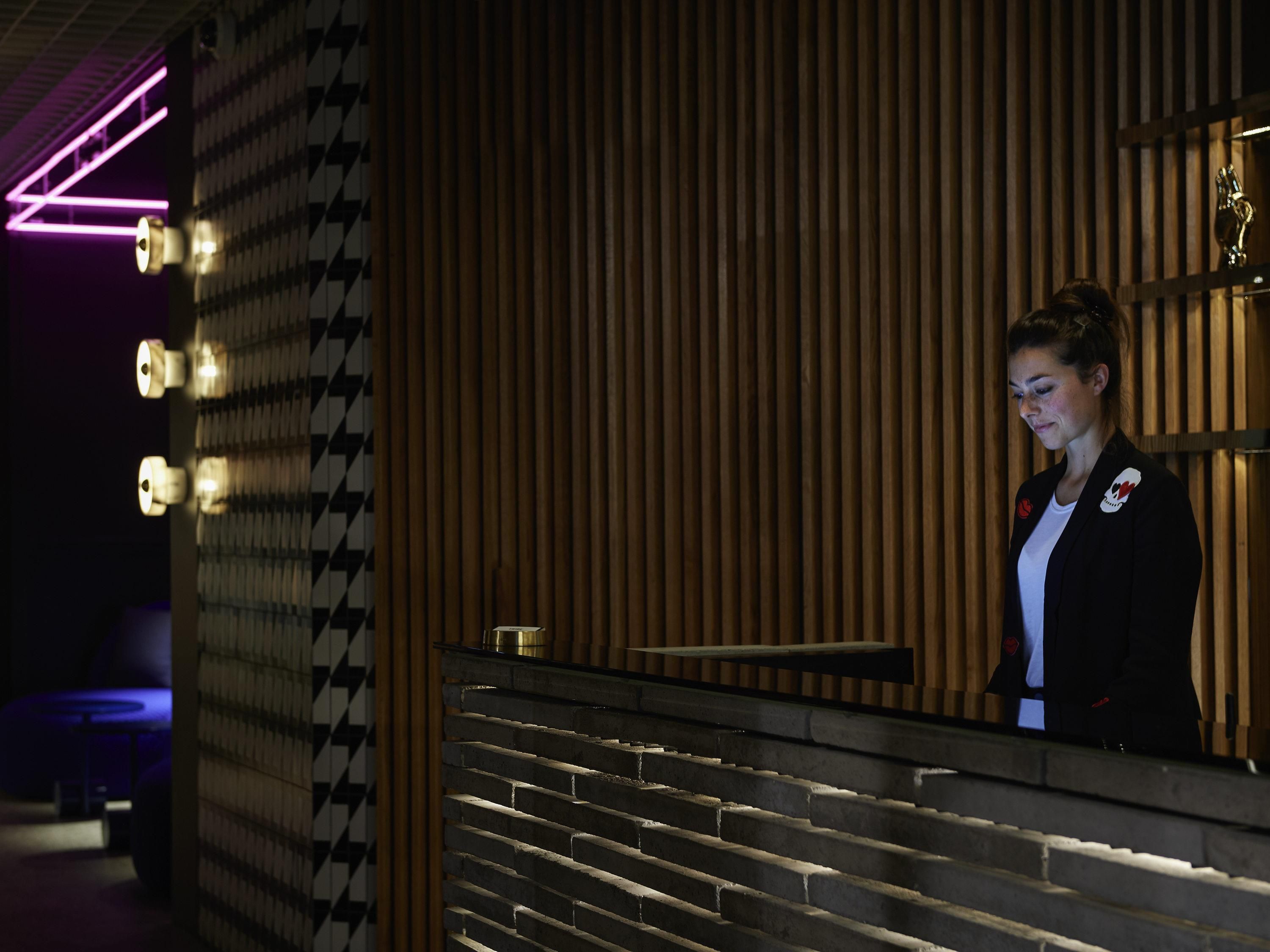 A reception area with a wooden panel wall, a reception desk, and a neon sign.